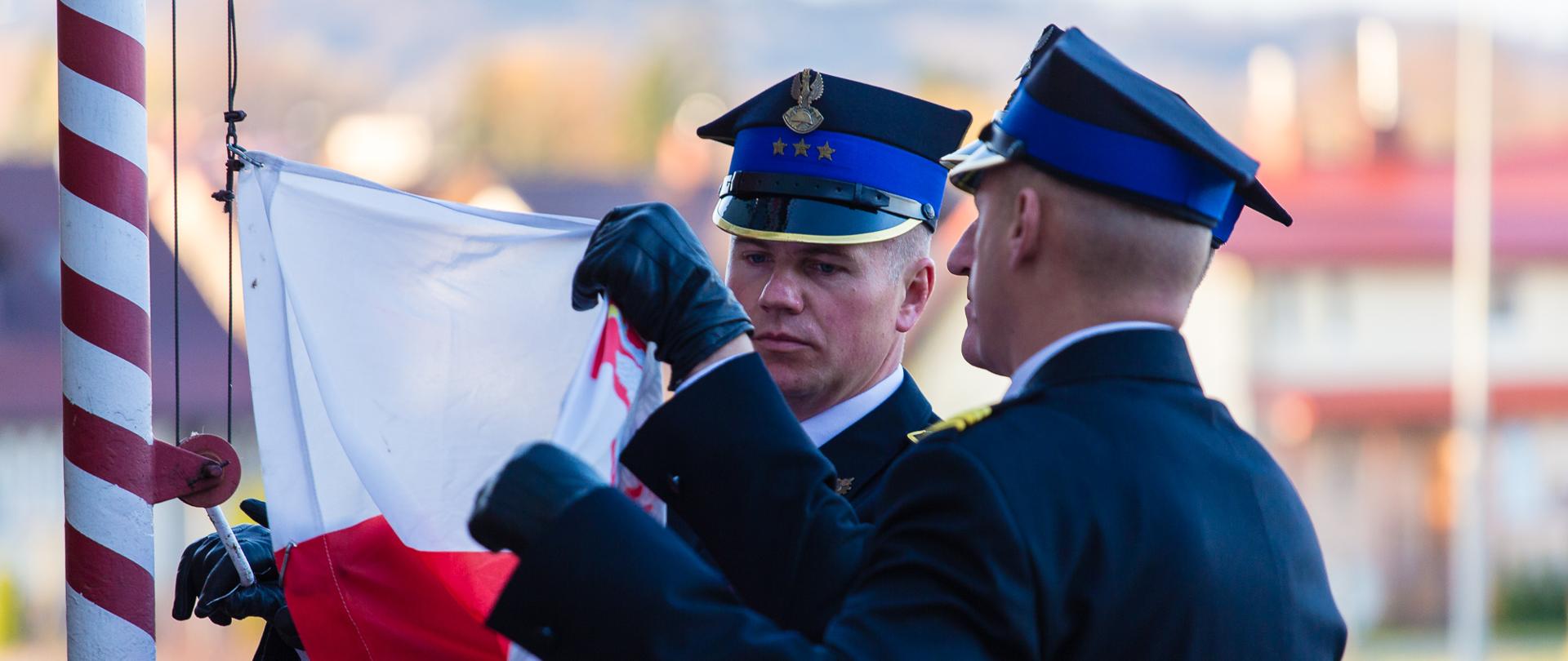 Zdjęcie przedstawia poczet flagowy, który mocuje flagę do masztu.