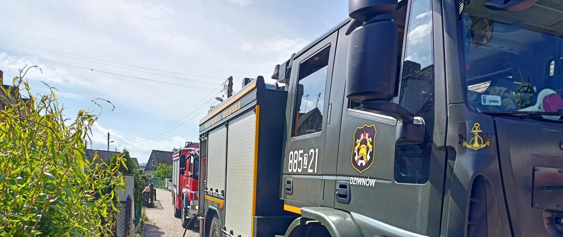 Dwa pojazdy straży pożarnej na drodze osiedlowej.