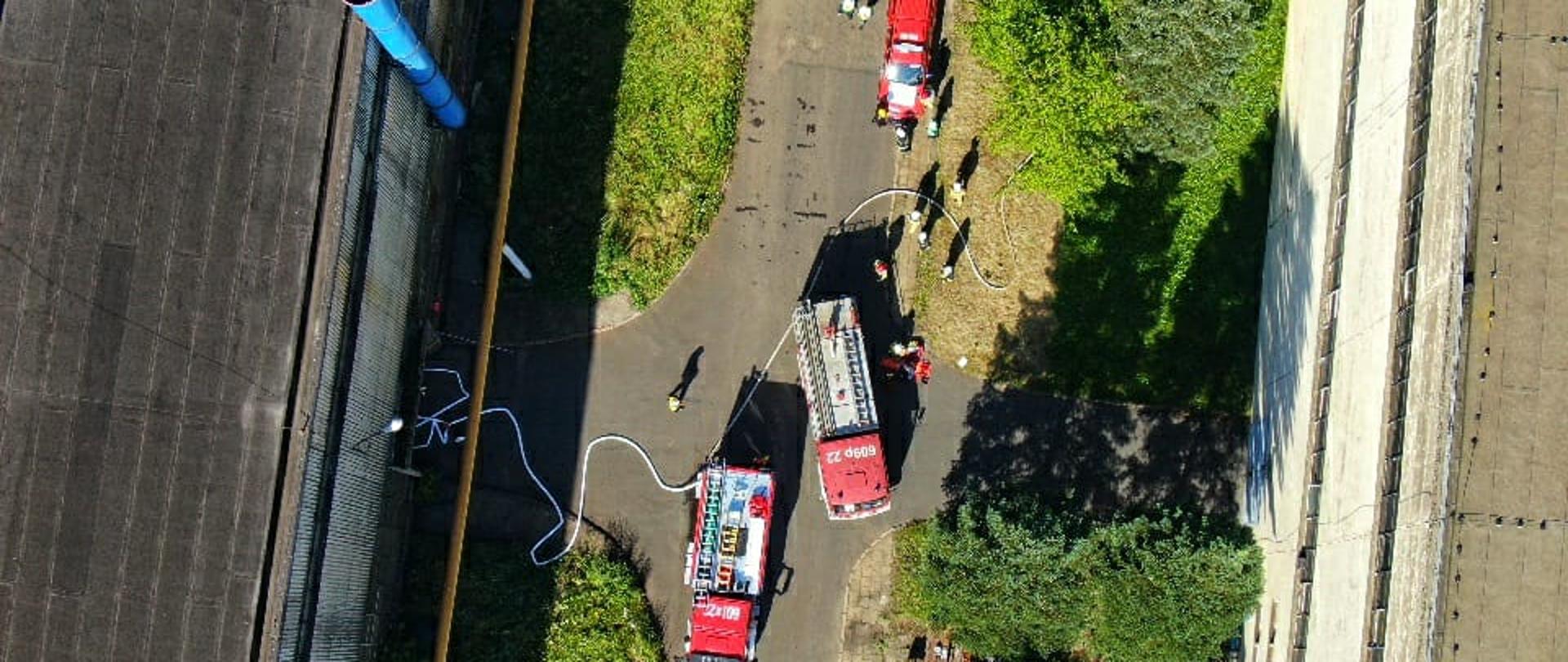 Na zdjęciu z drona widać zakład Odlewni żeliwa przed nim samochody ratowniczo-gaśnicze oraz strażacy 