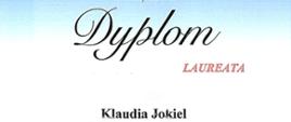 Na cieniowanym, jasno-niebieskim tle od góry logo Słupeckich Spotkań Muzycznych z gitarą i akordeonem, niżej jest napisane dyplom lauerata Klaudia Jokiel Państwowa Szkoła Muzyczna I stopnia im. A. Tansmana w Kępnie, jeszcze niżej znajduje się pieczątka organizatora, podpisy jurorów i na samym dole grafika budynków. 