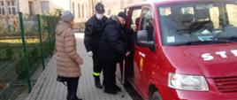 Strażacki bus przewozi seniora na szczepienie. Na zdjęciu widać jak senior wsiada do czerwonego busa.