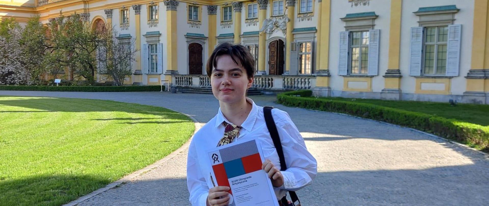 Fotografia przedstawiająca uczennicę PLSP w Katowicach na tle pałacu w Wilanowie.