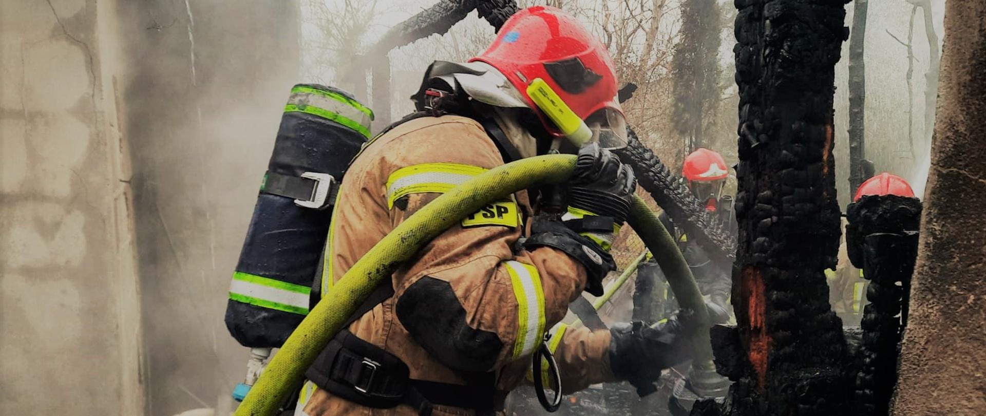 Strażak dogasza pogorzelisko 