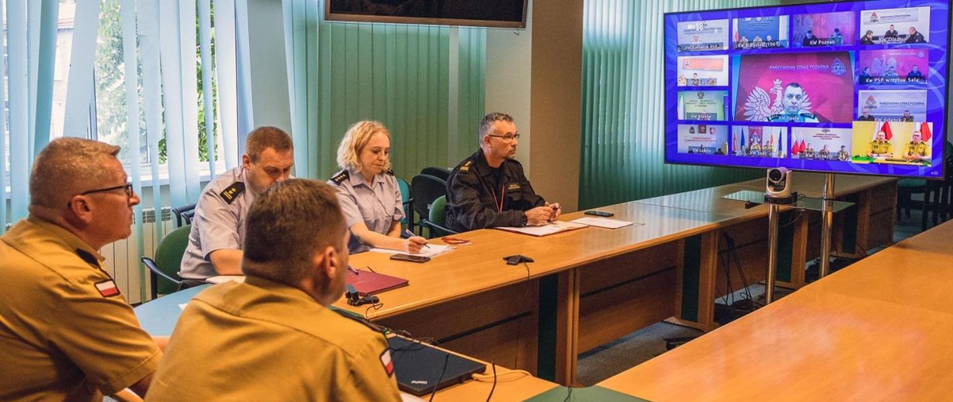 Na zdjęciu widzimy funkcjonariuszy Państwowej Straży Pożarnej w mundurach służbowych w trakcie wideokonferencji.