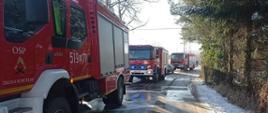 trzy samochody pożarnicze stojące na ulicy przed posesją na której doszło do pożaru