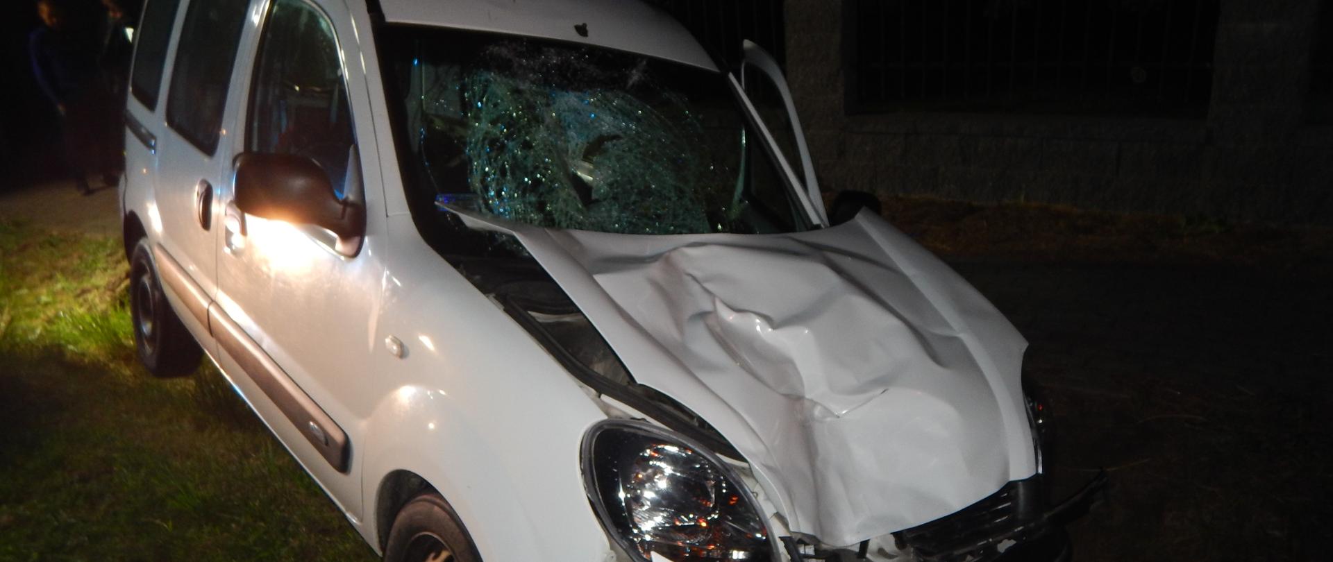 Zdjęcie przedstawia uszkodzony przód samochodu osobowego oraz rozbitą przednią szybę