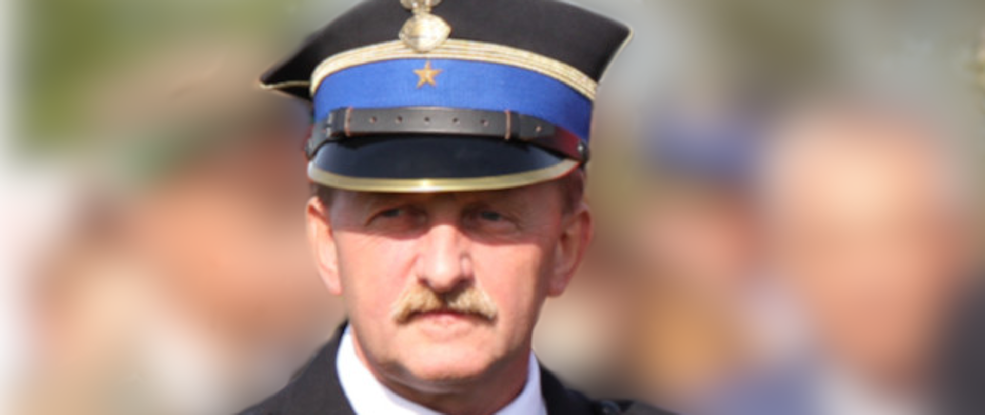 Strażak w mundurze wyjściowym, tło rozmyte.