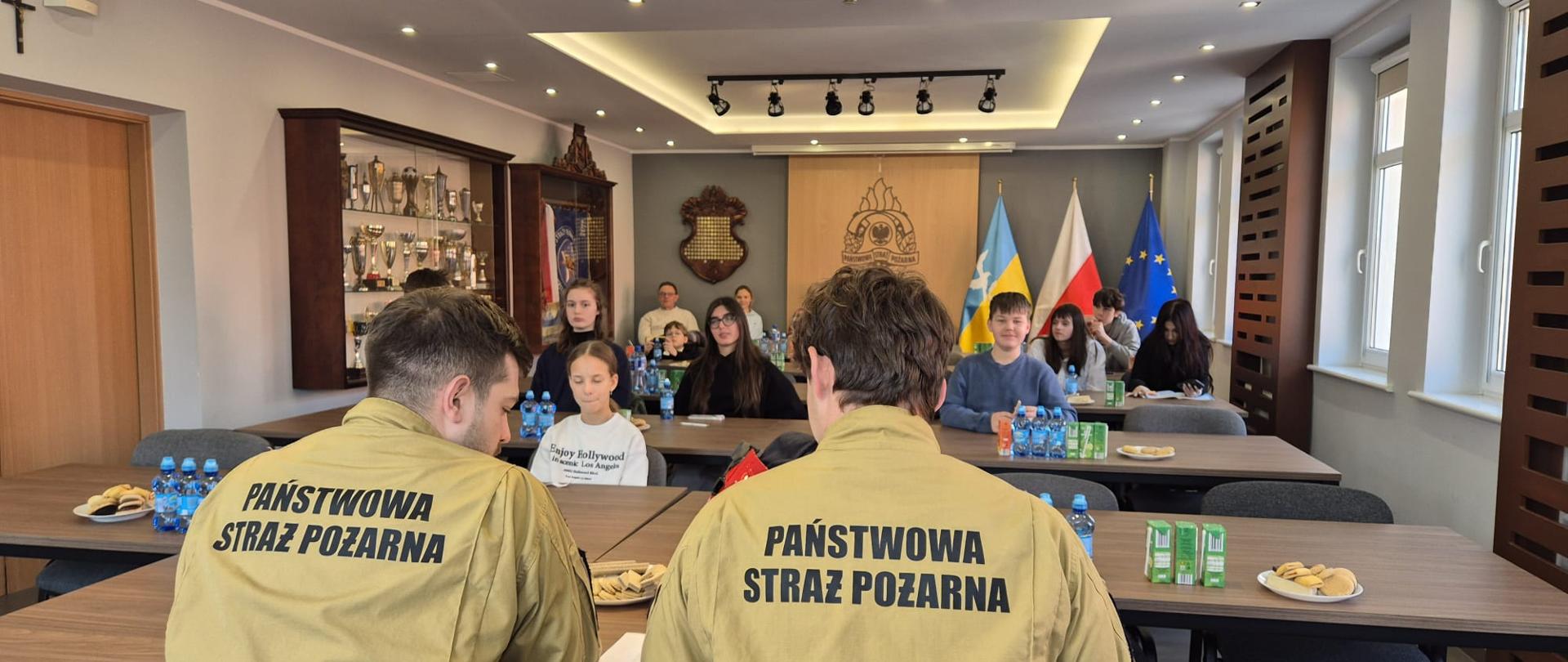 Na pierwszym planie widać komisje turnieju złożoną z dwóch strażaków za nią widać uczestników turnieju.