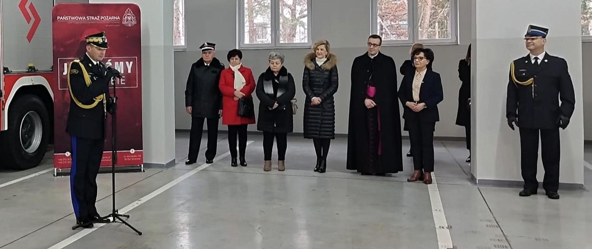 Obraz przedstawia Zastępcę Komendanta Głównego w trakcie przemówienia. W tle pozostali goście zaproszeni. 