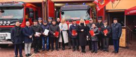 Parlamentarzyści, funkcjonariusze Państwowej Straży Pożarnej oraz druhowie, którzy otrzymali świadczenia ratownicze stoją przed budynkiem remizy Ochotniczej Straży Pożarnej w Ostrzeszowie.