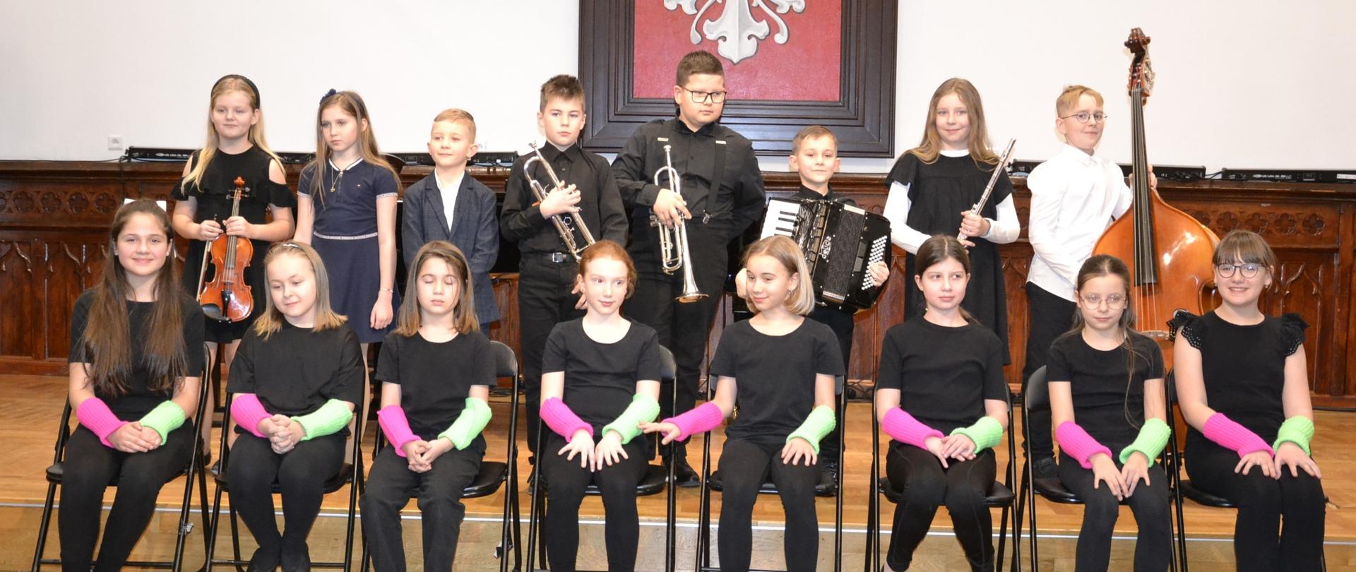 Grupowe zdjęcie uczniów klasy IIIA PSM I stopnia na scenie Sali Królewskiej po koncercie klasowym.