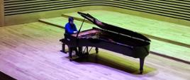 Mężczyzna gra na fortepianie na estradzie sali koncertowej