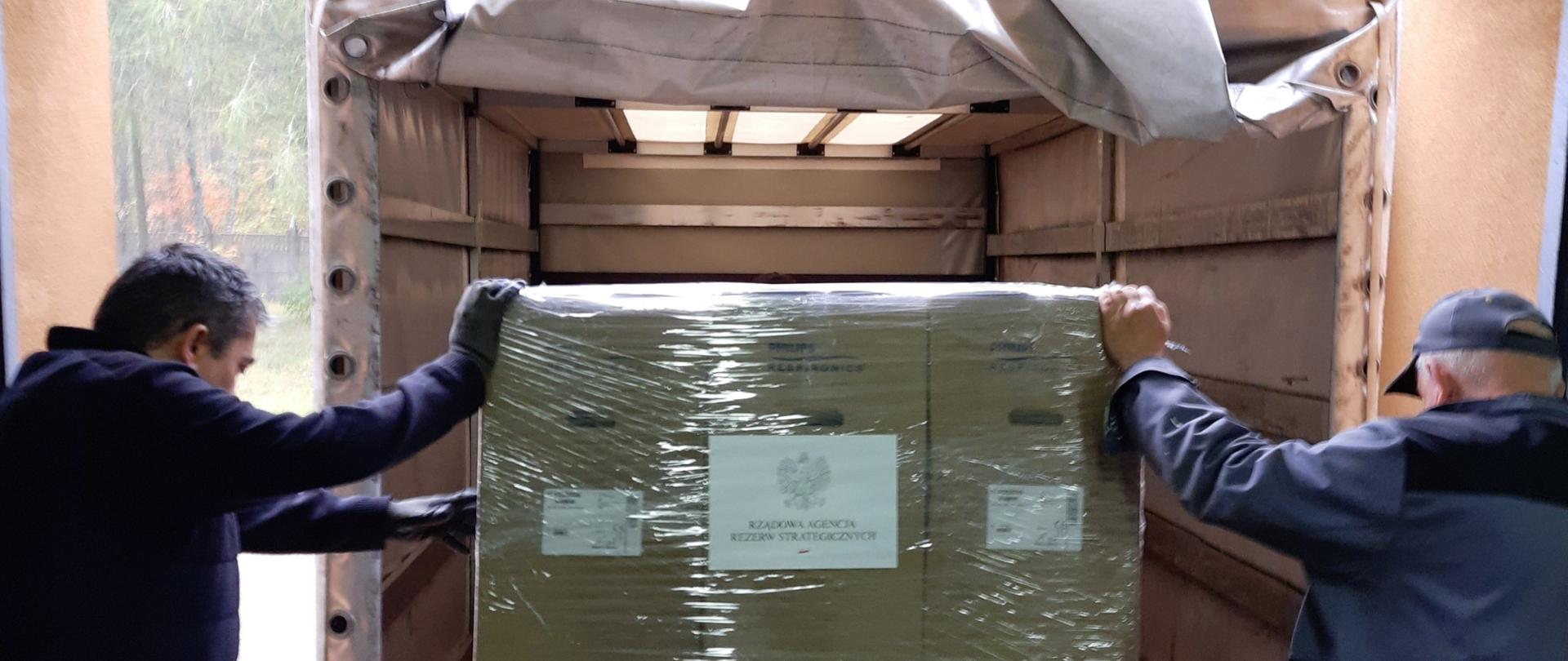 Dwóch mężczyzn umieszcza duże paczki w ciężarówce