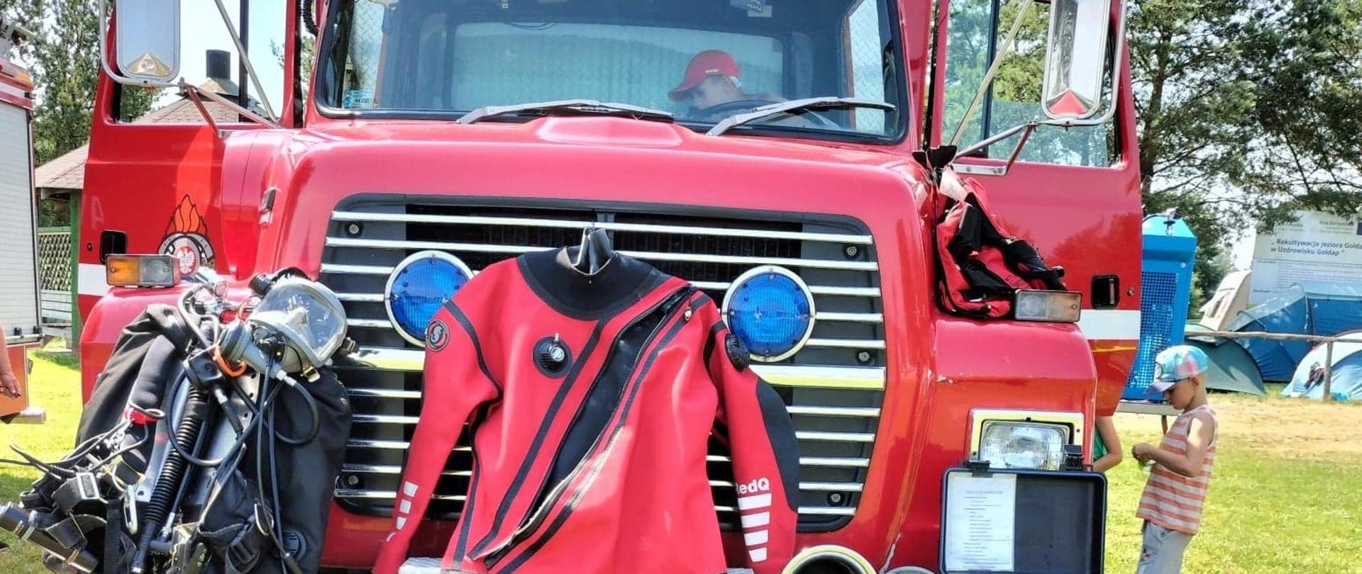 Pokaz sprzętu nurkowego na samochodzie SGRWN. W samochodzie widać dzieci, które oglądają pojazd. 