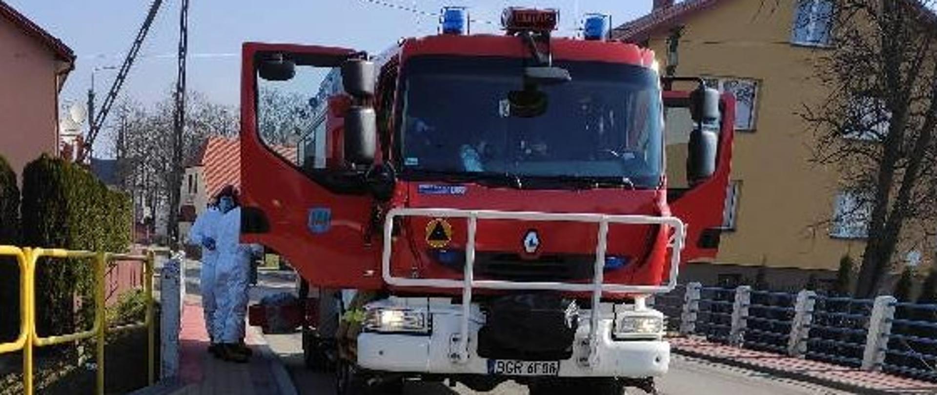 Samochód gaśniczy i strażacy ubraniach ochronnych.