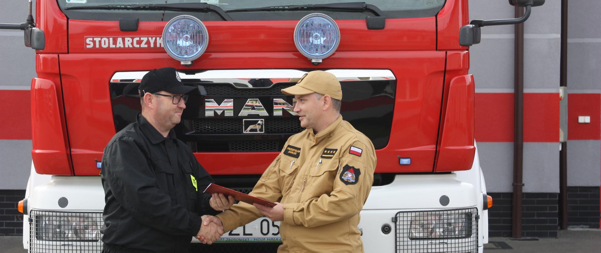 Samochód strażacki strażacy przed samochodem