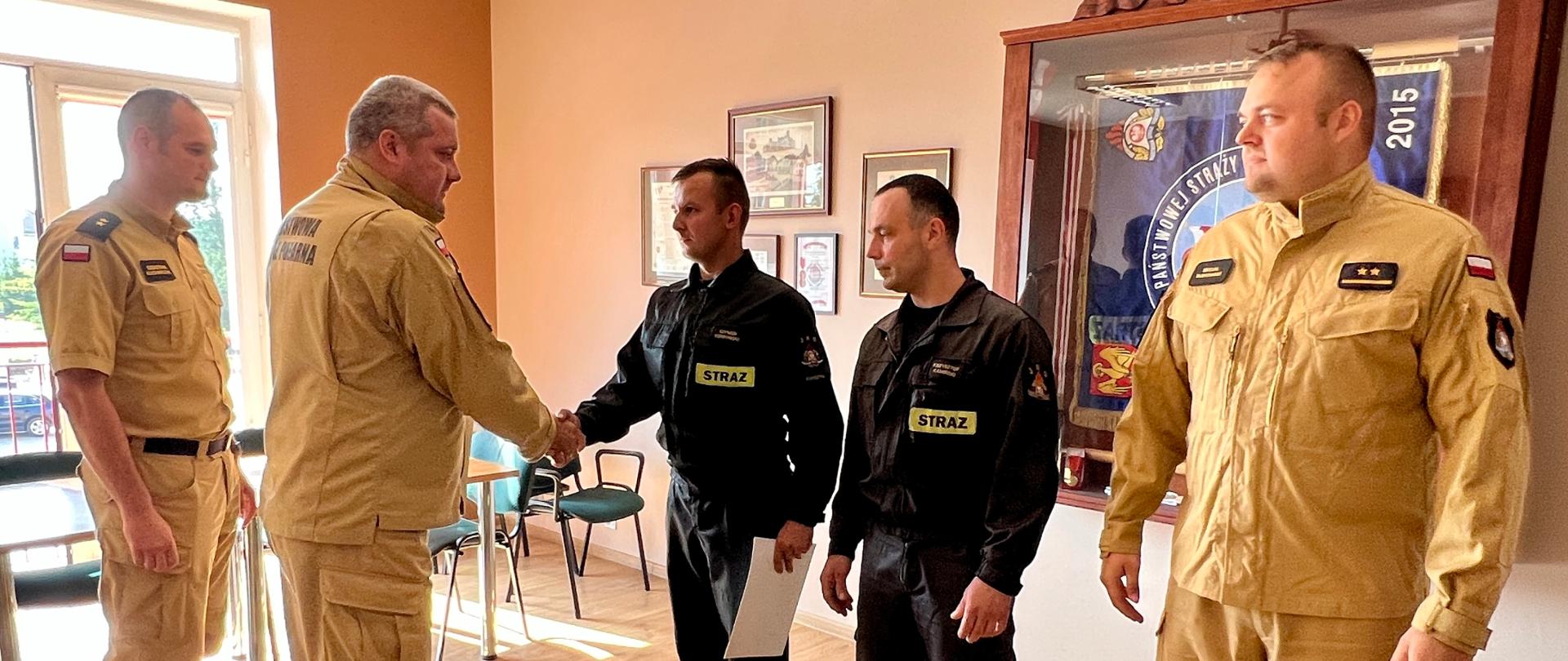 Komendant Powiatowy PSP w Kwidzynie wraz z Zastępcą wręczają strażakom akty mianowania na wyższe stanowiska służbowe.