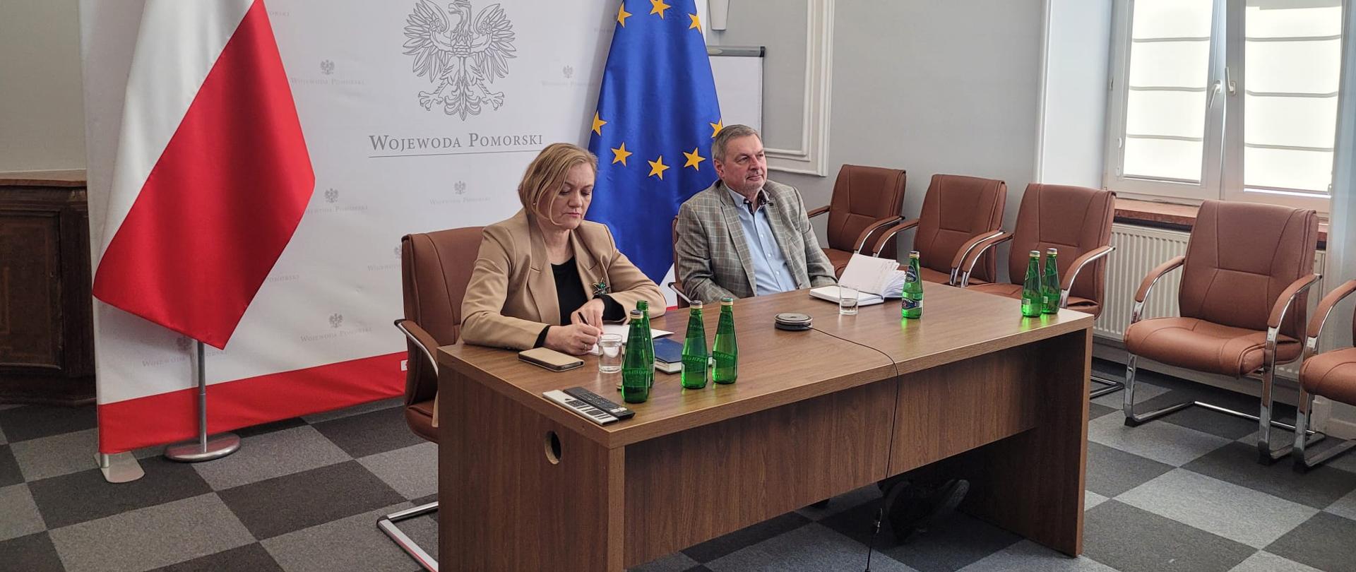 dwie osoby siedzą przed ekranem 