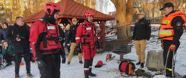 Zdjęcie przedstawia strażaków podczas pokazów ratownictwa lodowego. W tle uczestnicy pokazów.