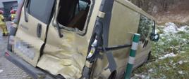 Kolizja dostawczaków. Droga gminna w Dębnie Polskim. Na pierwszym planie renault trafic - jeden z pojazdów biorących udział w kolizji. Auto częściowo znajduje się w rowie. Ma uszkodzoną tylna część. Z lewej strony widoczni są strażacy.