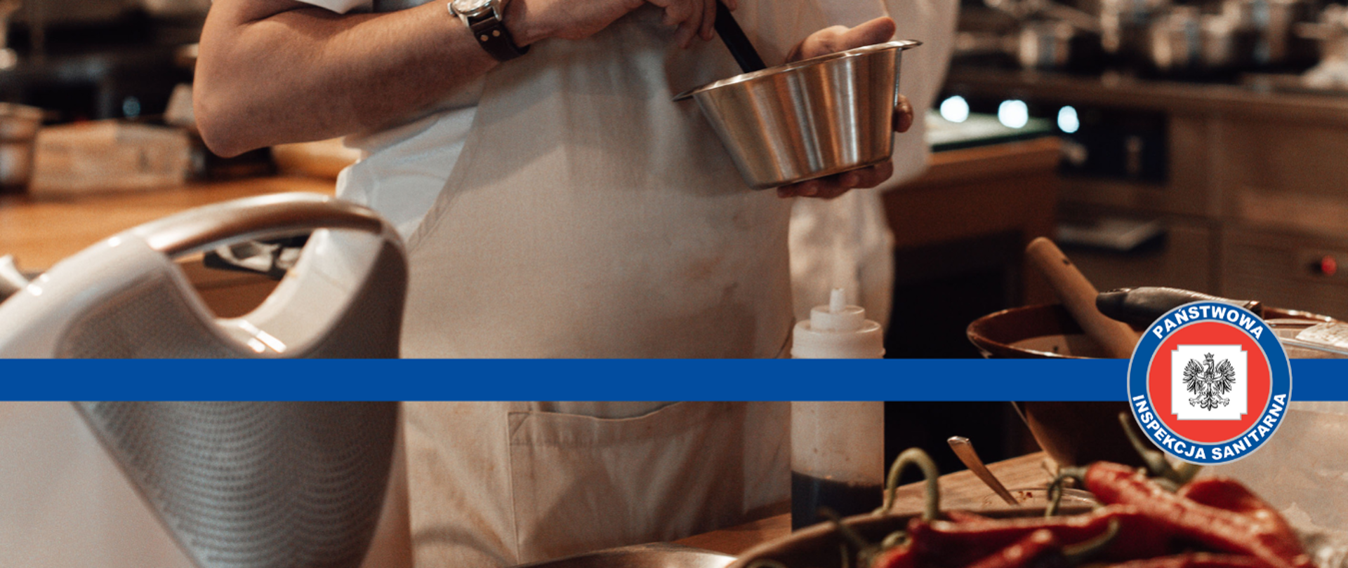 zdjęcie częściowo przedstawiające pracownika gastronomii wykonującego jakąś potrawę, na środku zdjęcia znajduje się logo Państwowej Inspekcji Sanitarnej.