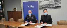 Zachodniopomorski Komendant Wojewódzki Państwowej Straży Pożarnej st. bryg. Jarosław Tomczyk z wiceprezesem ENEA Operator zawierający umowę. W tle baner ENEA operator, panorama stoczni szczecińskiej.