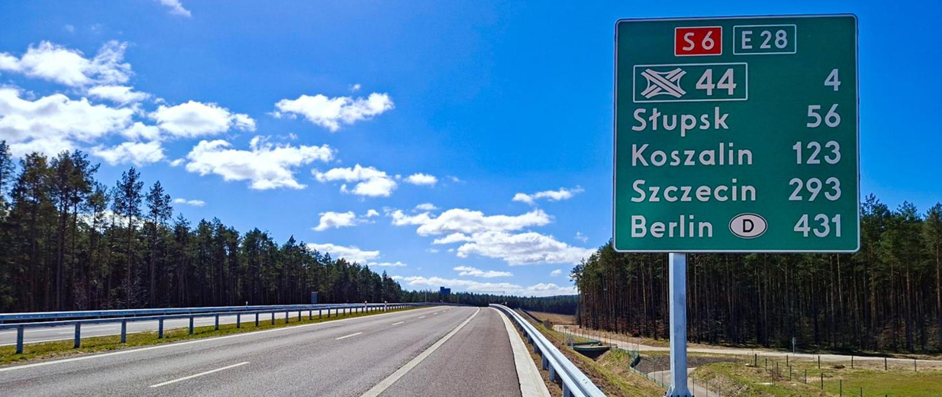 Droga ekspresowa S6 biegnąca przez teren leśny; po prawej stronie zielona tablica drogowa z oznaczeniami S6 i E28 oraz numerem 44, wskazująca kierunki i odległości do Słupska (56 km), Koszalina (123 km), Szczecina (293 km) i Berlina (431 km).