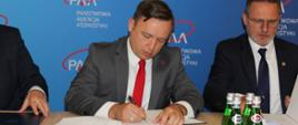 Na zdjęciu widoczny jest Prezes Państwowej Agencji Atomistyki Andrzej Głowacki podczas podpisywania porozumienia.