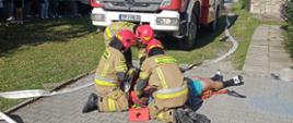 Strażacy podczas ćwiczeń taktyczno- bojowych na obiekcie wykonują czynności medyczne.