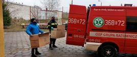 Strażak i ratownik pakują maseczki ochronne do samochodu Grupy Ratowniczej "Nadzieja"