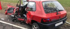 Zdjęcie przedstawia uszkodzony samochód osobowy koloru czerwonego 