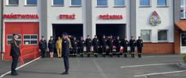 Zdjęcie przedstawie funkcjonariuszy Państwowej Straży Pożarnej podczas składania meldunku przez dowódcę uroczystości komendantowi powiatowemu PSP