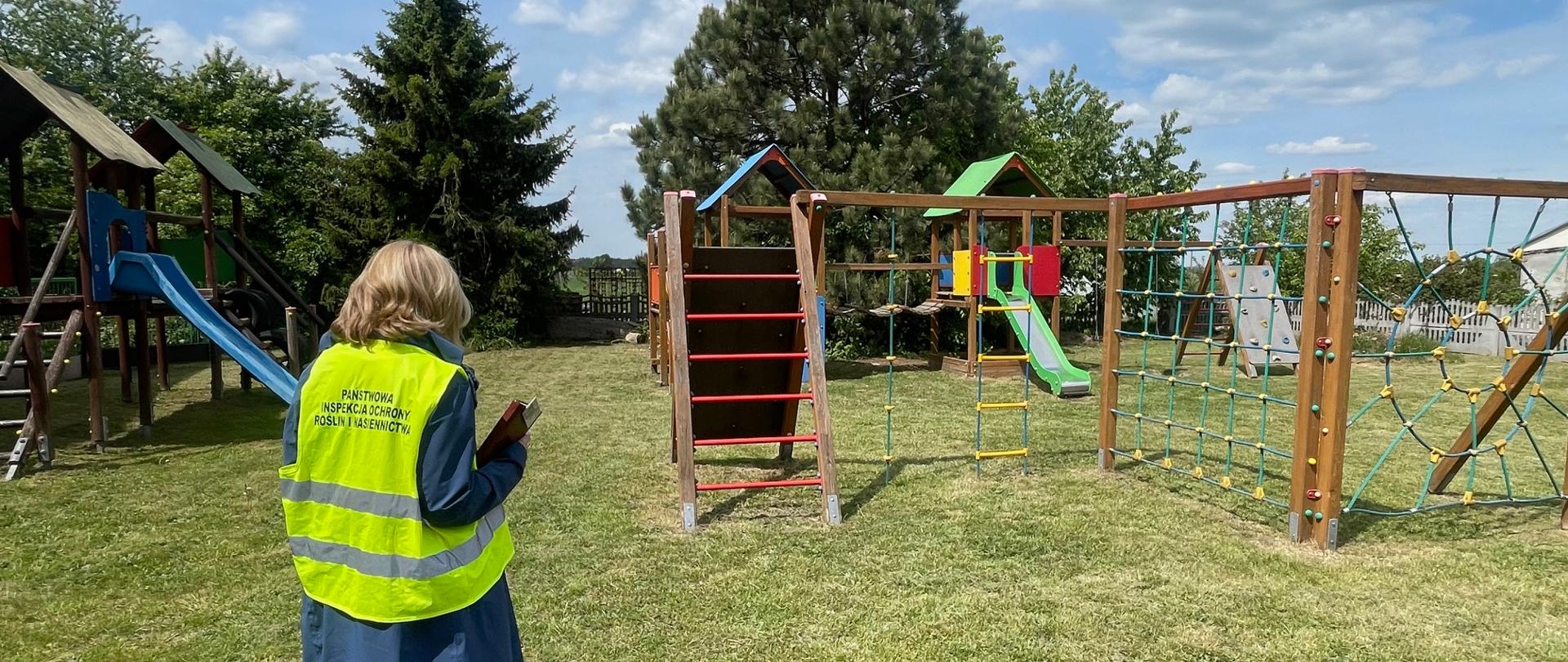 Zdjęcie przedstawia inspektora kontrolującego plac zabaw