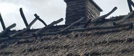Widoczne miejsce zdarzenia dach kryty strzechą, fragment dachu zniszczony w wyniku pożaru.