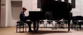 Chłopiec gra na fortepianie na estradzie auli PSM
