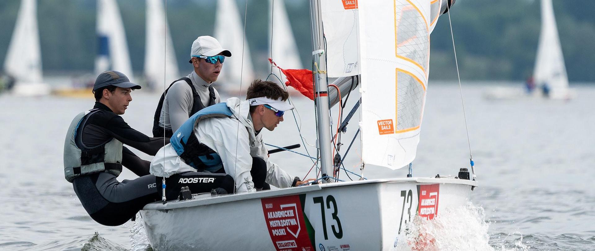 Grupka młodych osób płynie w żaglówce