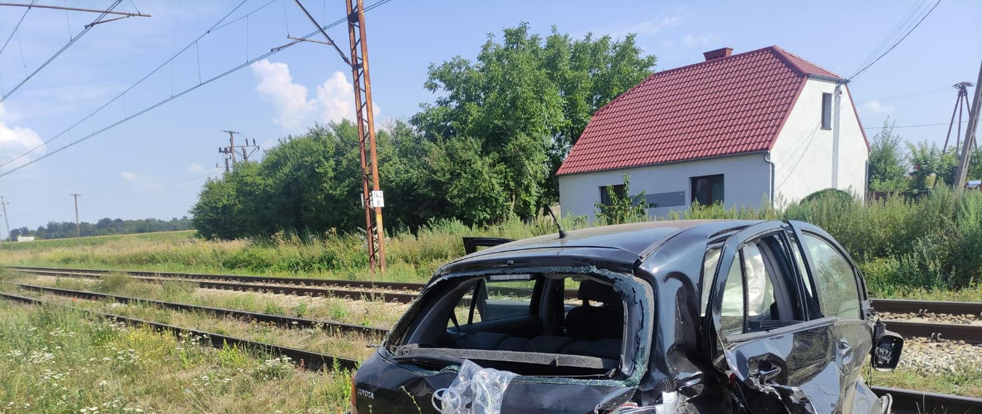 Zdjęcie przedstawia pojazd osobowy znajdujący się na torowisku po zderzeniu z drezyną.