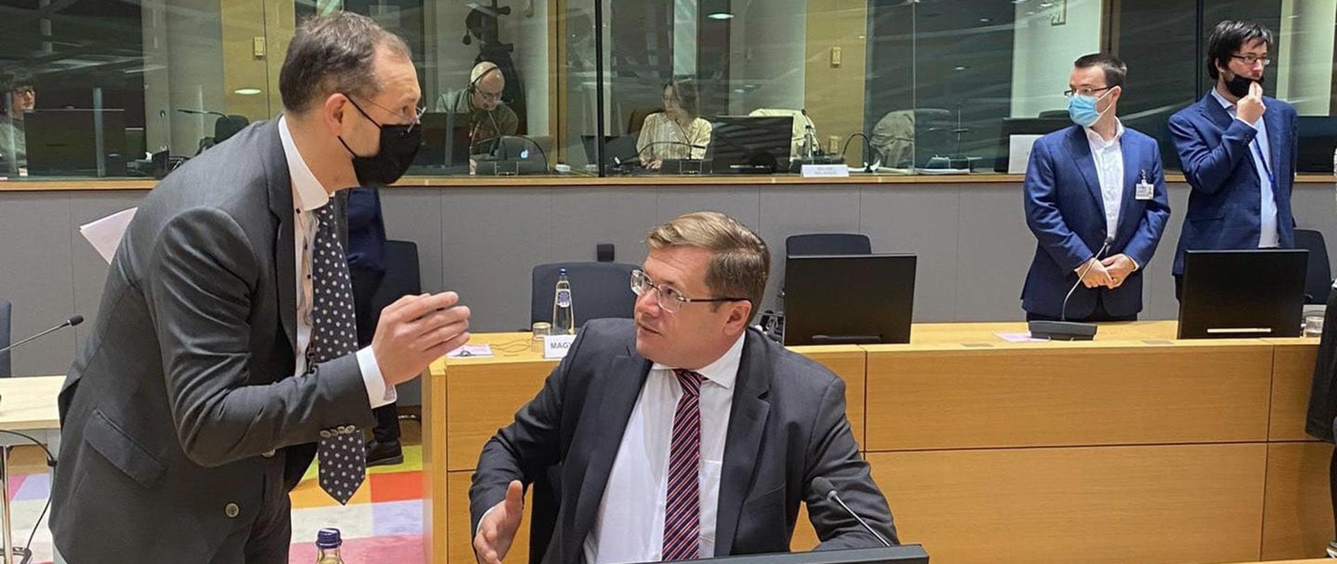 Dwóch uczestników spotkania na temat budżetu na 2022 r. rozmawia podczas przerwy w spotkaniu na sali plenarnej.