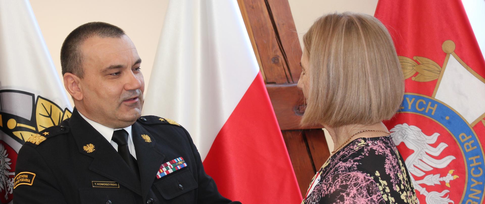 Komendant wojewódzki PSP podaje rękę kobiecie. 