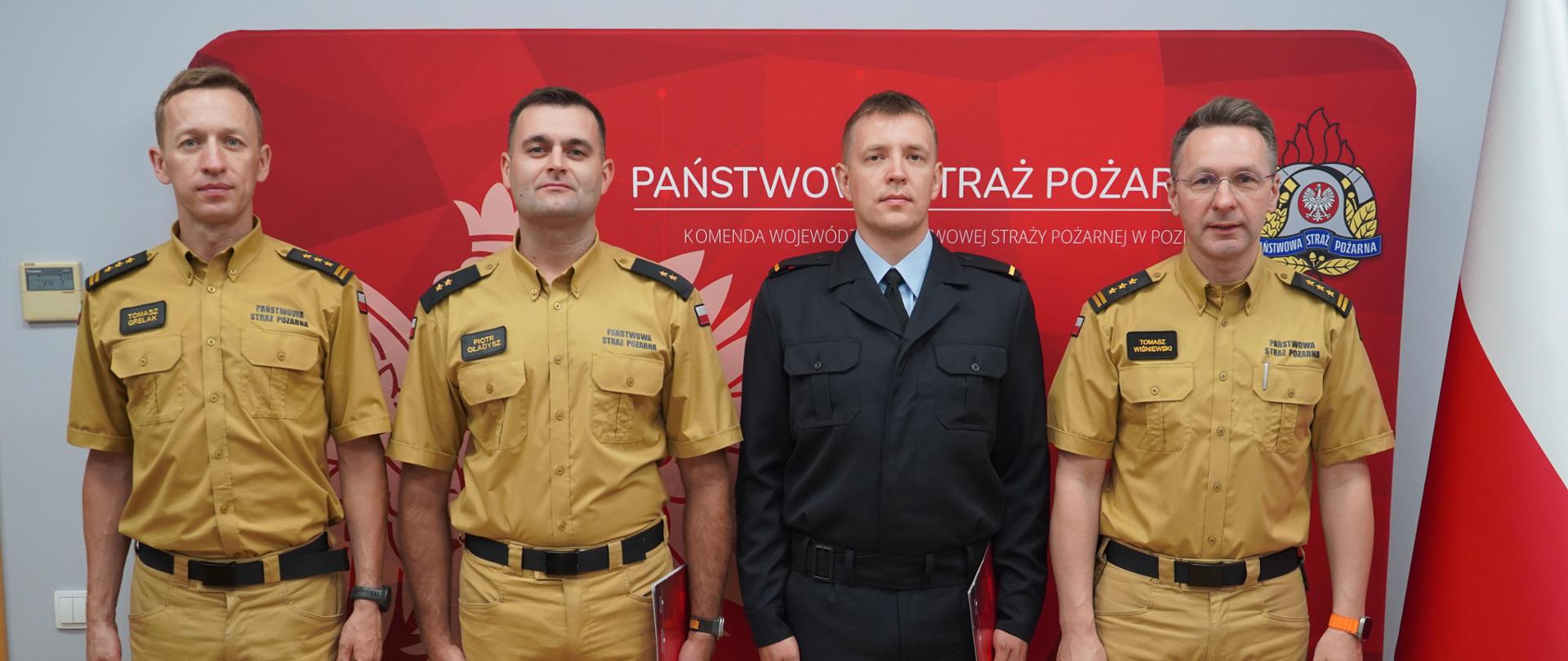 Strażacy mianowani na stanowiska wspólnie z Komendantami. W tle ścianka PSP.