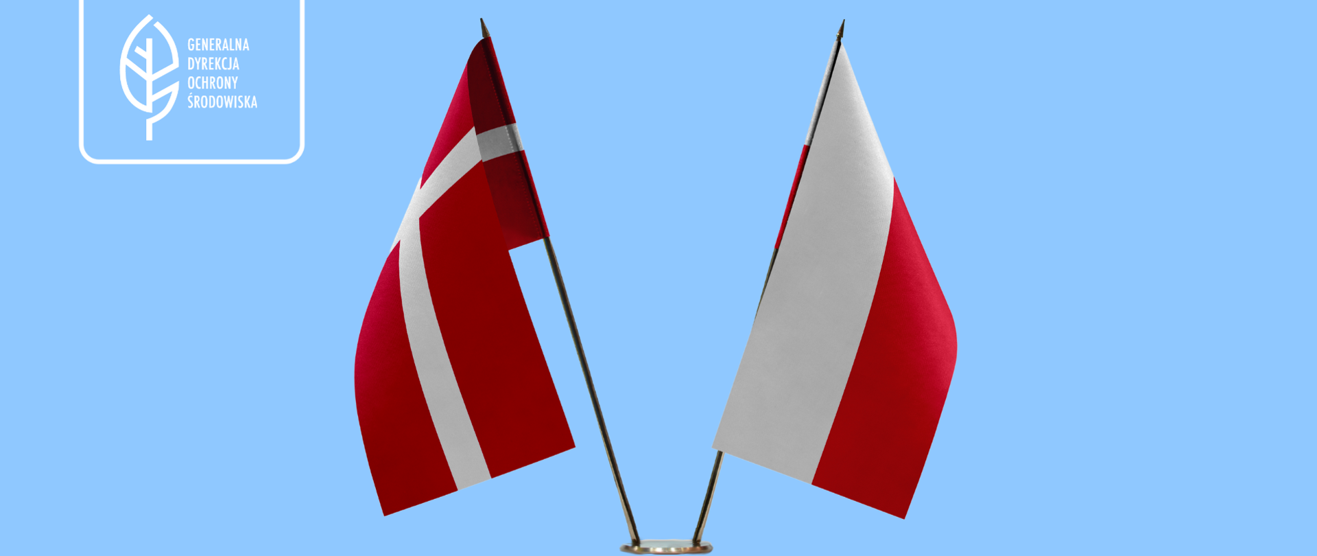 Na niebieskim na stojaku postawione są dwie flagi: Polski i Danii (obie w kolorach białym i czerwonym).
W prawym górnym rogu logotyp Generalnej Dyrekcji Ochrony Środowiska (biały liść).