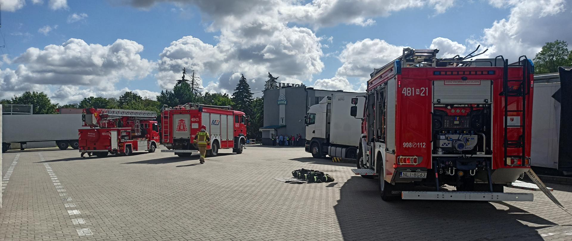 Zdjęcie przedstawia pojazdy pożarnicze ustawione podczas ćwiczeń w zakładzie mleczarskim POLMLEK