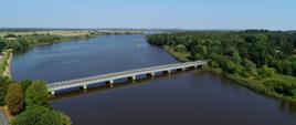 Na zdjęciu widać most drogowy dziewięcioprzęsłowy na rzece. Brzegi rzeki porośnięte lasami.