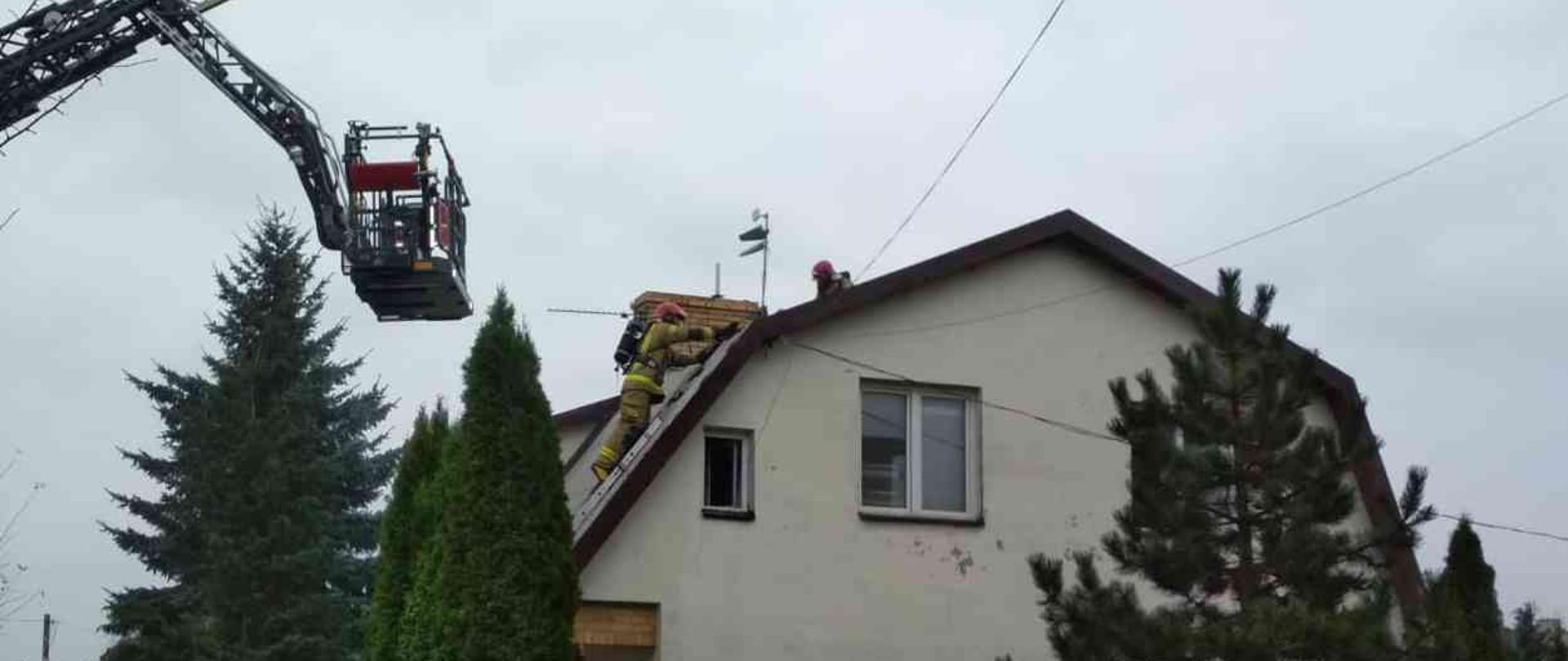Na zdjęciu widać strażaków pracujących na dachu z drabin