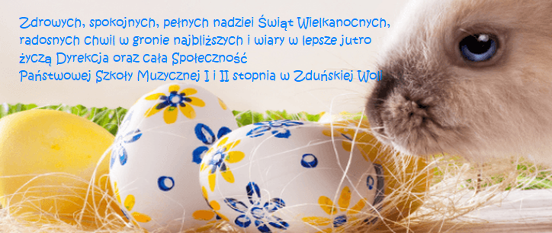 Grafika przedstawia na kremowym tle od lewej u góry napis zdrowych, spokojnych, pełnych nadziei Świąt Wielkanocnych, radosnych chwil w gronie najbliższych i wiary w lepsze jutro życzą Dyrekcja oraz cała społeczność państwowej szkoły muzycznej I i II stopnia w zduńskiej woli. Obok pysk królika, a na dole znajdują się pisanki w niebiesko-żółte wzory