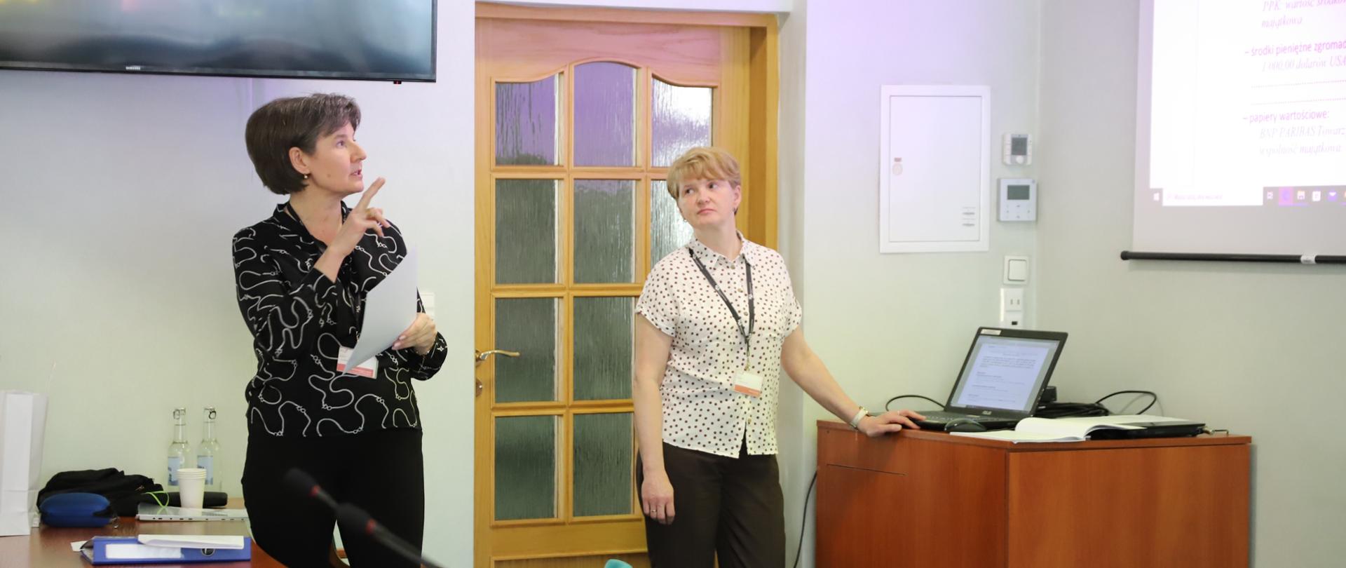 Ekspertki stoją przed ekranem, na którym wyświetlana jest prezentacja