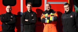 1. Mistrzostwa Pierwszej Pomocy - czterej strażacy biorący udział w wydarzeniu na tle samochodu