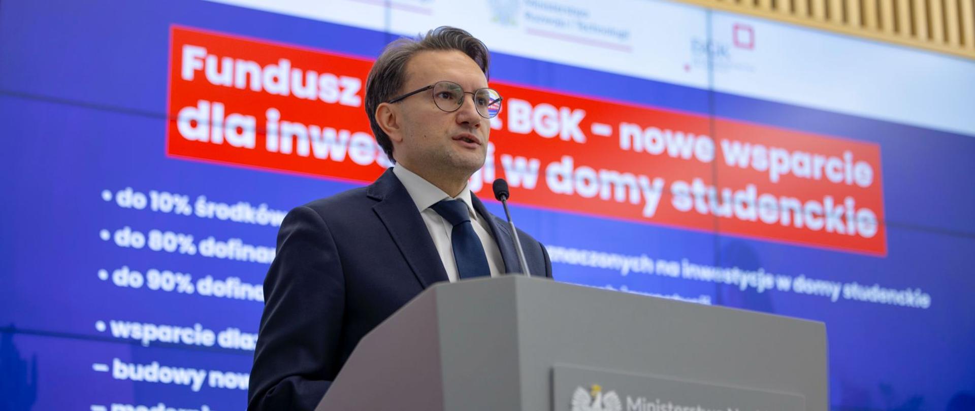 Wiceminister MRiT Tomasz Lewandowski przemawia na konferencji prasowej nt. startu programu wsparcia domów studenckich - ujęcie od dołu