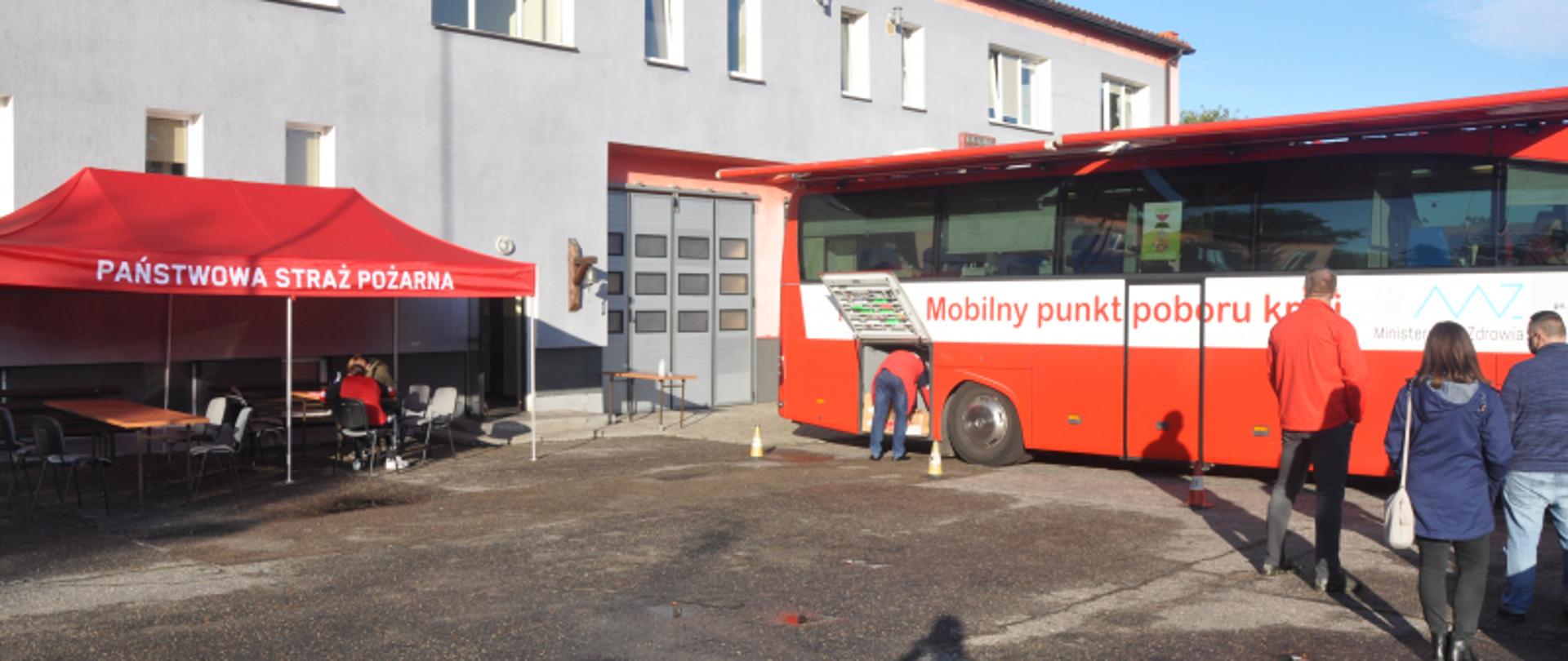 
Na zdjęciu widoczny budynek KP PSP w Lidzbarku Warmińskim. Po prawej stronie budynku widzimy mobilny punk poboru krwi – autobus, oraz osoby deklarujące chęć honorowego oddania krwi.
