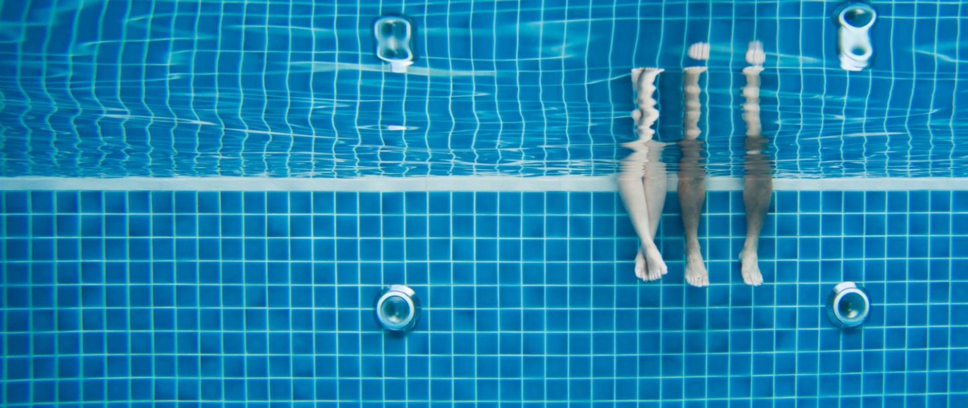 Zdjęcie pod wodą na basenie z widocznymi zanurzonymi nogami
